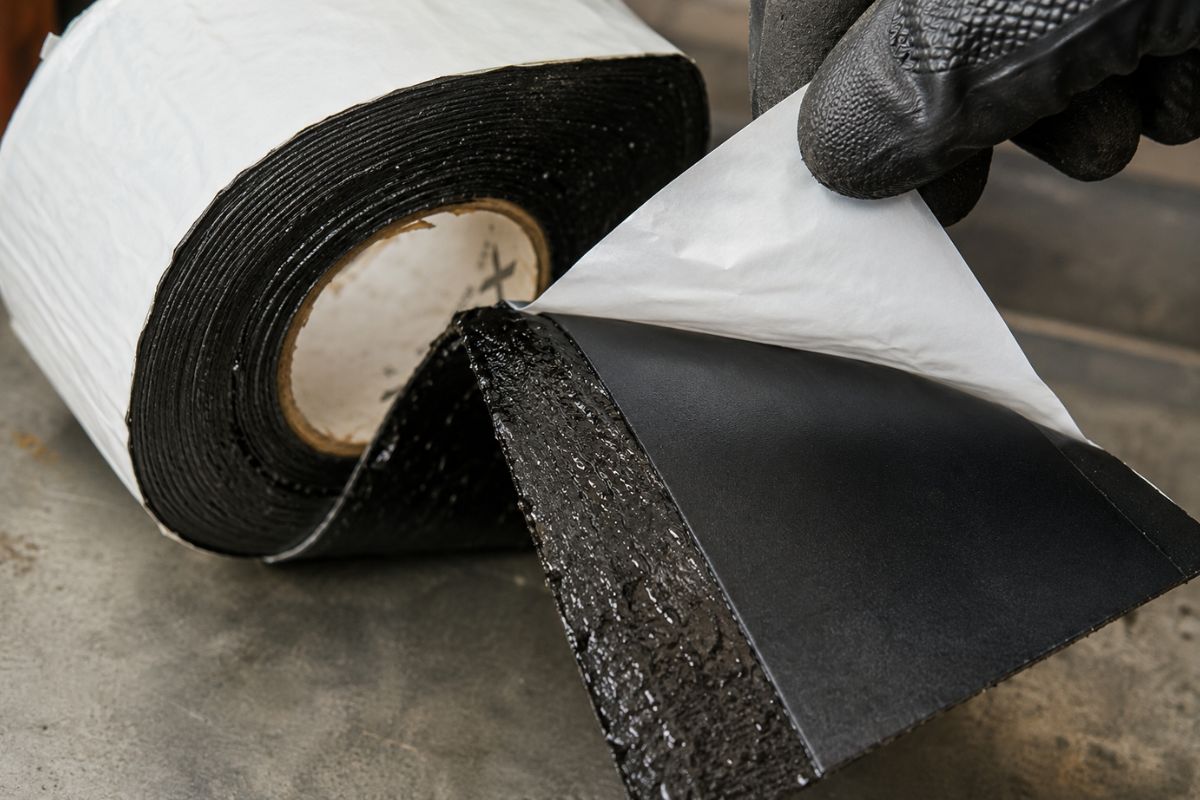 Cận cảnh thao tác bóc tách lớp màng Polyethylene để lộ lớp keo bitum siêu bám dính của băng quấn Xunda T300.
